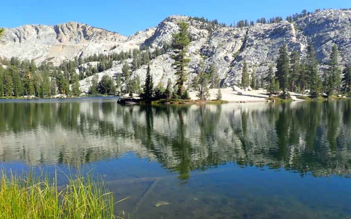 a body of water lies among trees and hills in yosemite